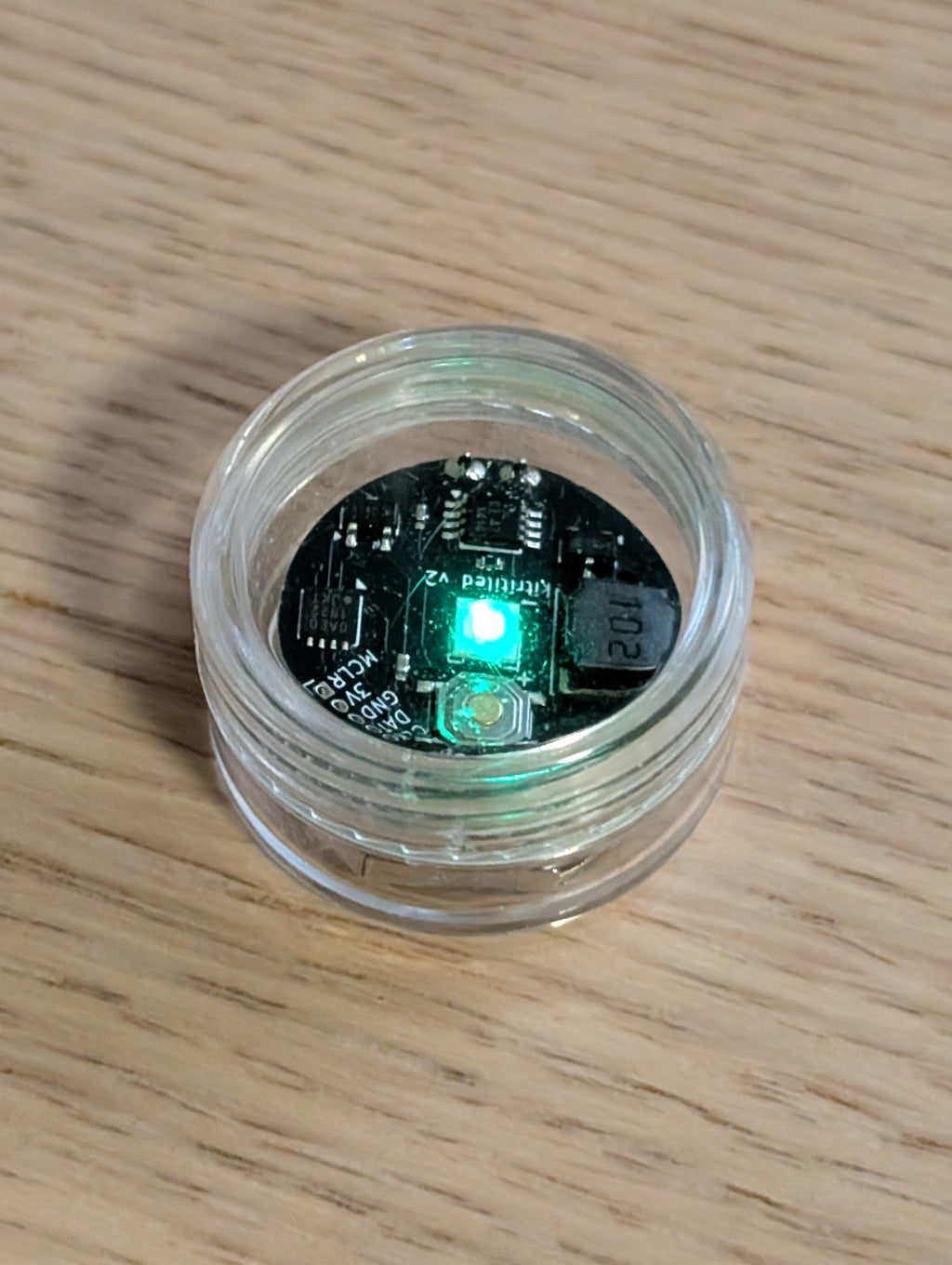 Small electronic component in a clear container on a wooden surface